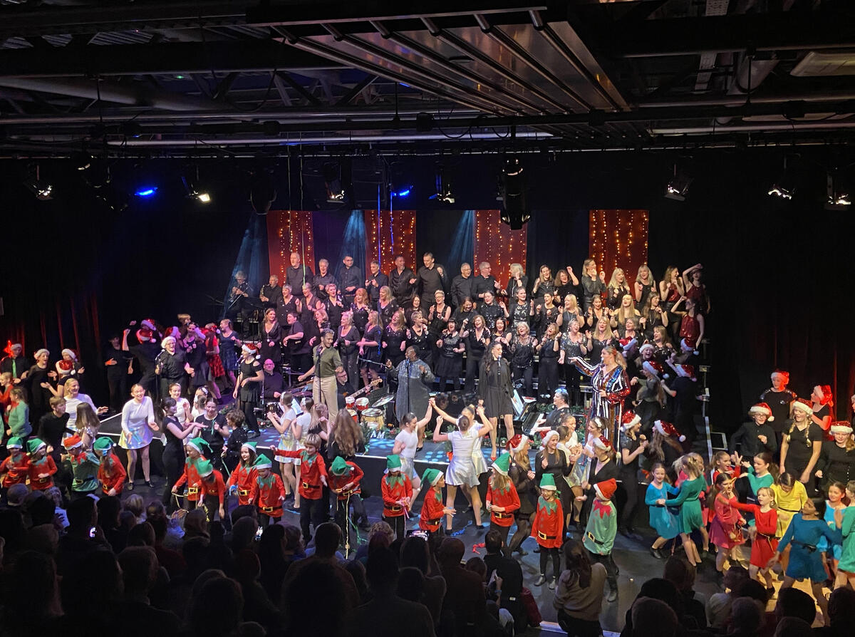 A crowded stage of actors, dancers, singers, and the audience on looking.